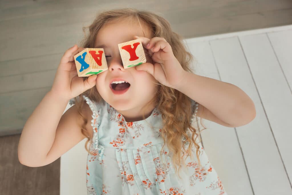 50+ R Girl Names to Consider for Your Daughter | Rebecca is the most popular R girl name in the U.S. over the last 100 years. Baby Names young girl holding alphabet blocks by eyes