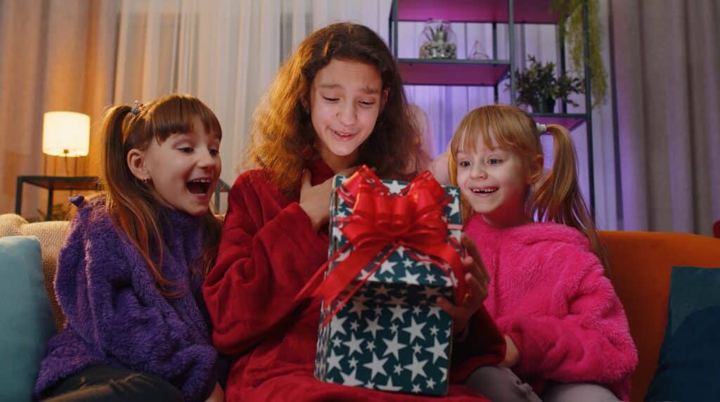 Why Kylie Kelce refuses to give ‘sibling gifts’ and 10 alternatives for parents who agree | "I am vehemently against the idea of other kids getting birthday presents on a child's birthday.” Pregnancy News daughters opening gift box