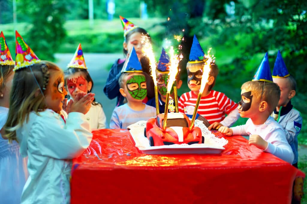 Why Kylie Kelce refuses to give ‘sibling gifts’ and 10 alternatives for parents who agree | "I am vehemently against the idea of other kids getting birthday presents on a child's birthday.” Pregnancy News kids at birthday party eating cake with sparklers