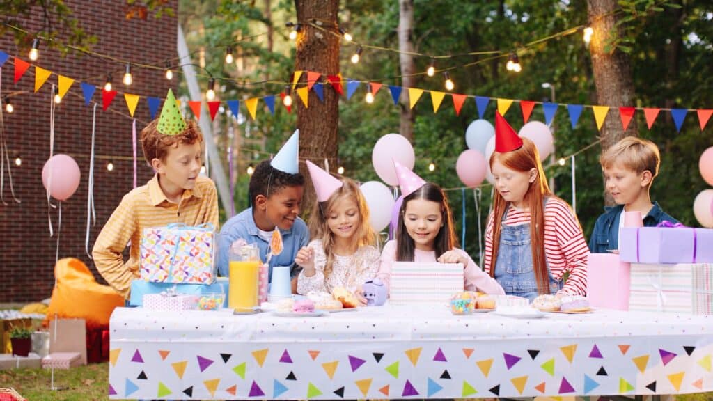 Why Kylie Kelce refuses to give ‘sibling gifts’ and 10 alternatives for parents who agree | "I am vehemently against the idea of other kids getting birthday presents on a child's birthday.” Pregnancy News children watching young girl open birthday sibling gifts
