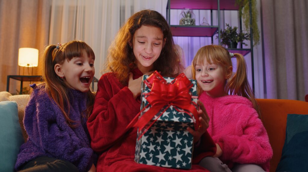 Why Kylie Kelce refuses to give ‘sibling gifts’ and 10 alternatives for parents who agree | "I am vehemently against the idea of other kids getting birthday presents on a child's birthday.” Pregnancy News daughters opening gift box