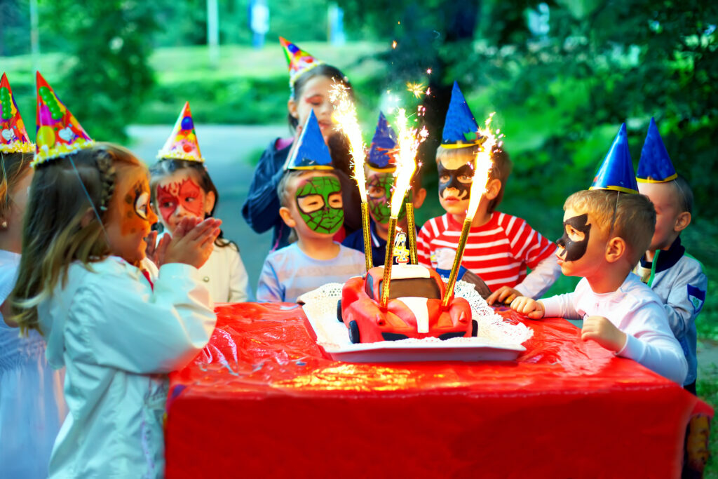 Why Kylie Kelce refuses to give ‘sibling gifts’ and 10 alternatives for parents who agree | "I am vehemently against the idea of other kids getting birthday presents on a child's birthday.” Pregnancy News kids at birthday party eating cake with sparklers