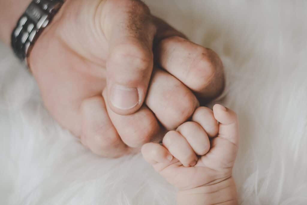 father and newborn baby fist bump