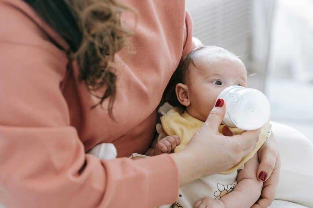 Experts are growing more concerned about the release of microplastics in plastic baby bottles | Recent research shows that an average infant consumes 1.6 million microplastic particles every day. Parenting mom giving baby a bottle