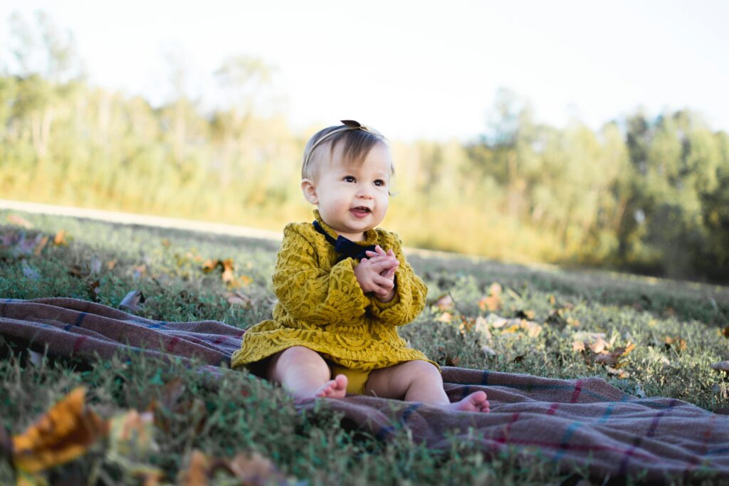 Fall-inspired baby girl names that feel as warm and cozy as your favorite autumn sweater | Autumn has arrived — so let’s give that baby name list of yours a much-needed fall makeover. Babies baby girl on grass during fall season