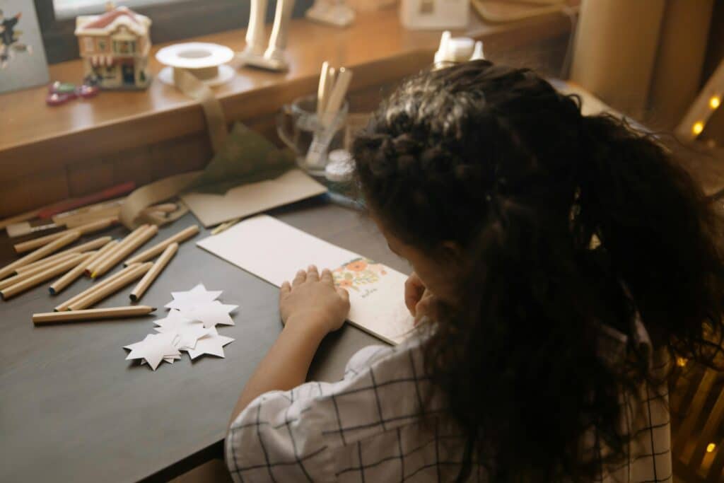 young girl writing pen pal letter on desk