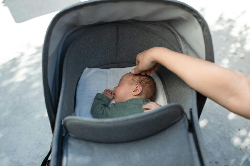 parent touches baby head while sleeping in vintage stroller