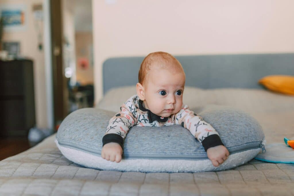 infant laying in a baby lounger on a bed