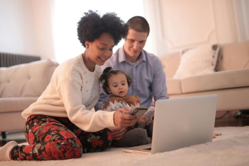parents scrolling through phone and laptop with baby girl most popular baby names